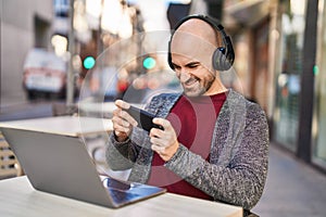 Young man smiling confident playing video game at coffee shop terrace