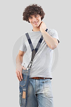 young man smiling and handsome dressed in jeans and t-shirt with shoulder bag isolated on gray background