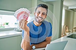 Young man smiling happy holding chinese yuan banknotes at home