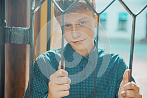 Young man smiling holding a metal grate with his hands