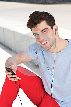 Young man smiling and listening to his mp3 player outdoors