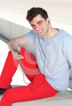 Young man smiling and listening to music on mp3 player