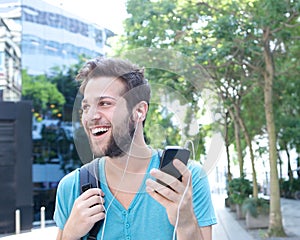 Young man smiling with mobile phone and earphones