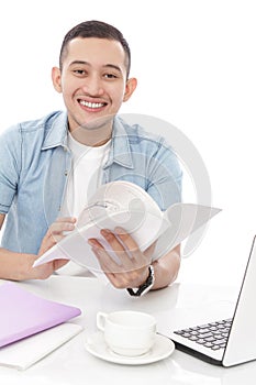 Young man smiling while reading a book