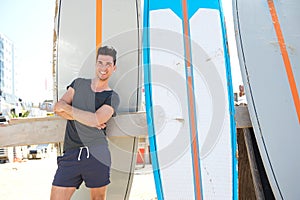 Young man smiling and standing with surfboard at the beach