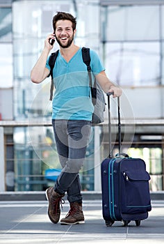 Young man smiling with suitcase at airport