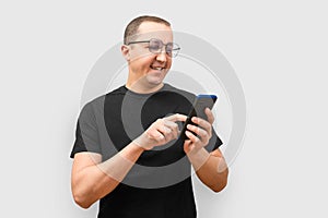 Young man smiling using phone on light background