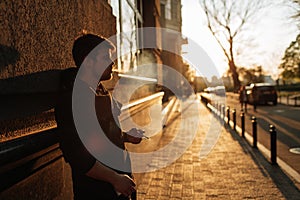 Young man smokes at sunset in the middle of the city