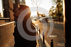 Young man smokes at sunset in the middle of the city