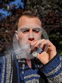 A young man smoking a cigar outside