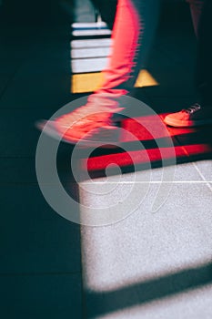 Young man in sneaker walking on the street. Bright light falling down through the colored glass windows on the floor