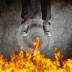 Young man in sneakers is jumping over fire