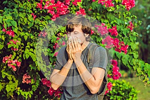 Young man sneezes because of an allergy to pollen