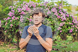 Young man sneezes because of an allergy to pollen