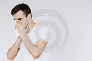 A young man sneezes into a napkin. Isolated white background photo