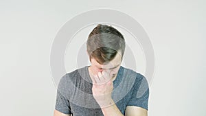 Young man sneezing on a white background. Portrait of sneezing man. Young man holding a tissue and sneezing on white