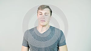 Young man sneezing on a white background. Portrait of sneezing man. Young man holding a tissue and sneezing on white