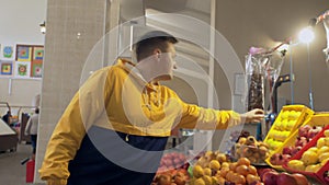 Young man sniffs and chooses a fresh apples in the market