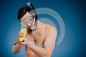 young man in snorkel and diving mask holding water gun