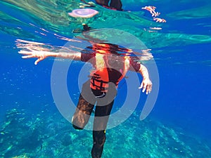 Young man snorkeling scuba diving with life jacket at the Great Barrier Reef in the tropical