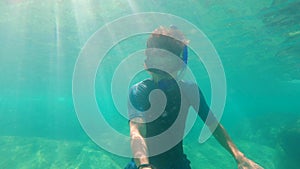 Young man snorkling in a beautiful blue sea and makes a selfie video