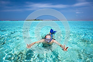 Young man snorkling in tropical lagoon with over water bungalows photo