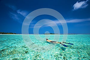 Young man snorkling in tropical lagoon with over water bungalows photo