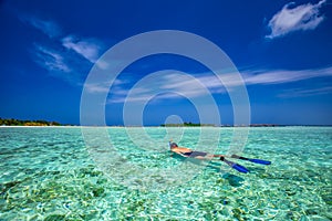 Young man snorkling in tropical lagoon with over water bungalows, Maldives photo