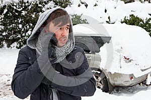 Young man in snow with broken down car