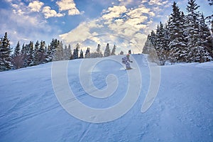 Young man snowboarder running down the slope in Karakol mountains.