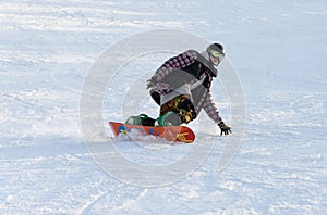 Young man snowboarding down the piste