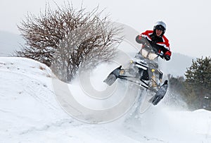 Young man on snowmobile jumping