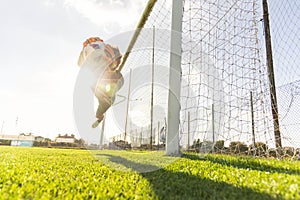 Young man soccer player is training alone for football at the stadium at sunset - Goalkeeper catches the ball