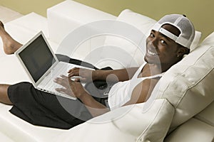 Young man on sofa using laptop high angle view portrait