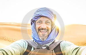 Young man solo traveler taking selfie at Erg Chebbi desert dune