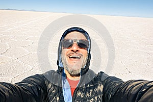 Young man solo traveler taking selfie at Salar de Uyuni saltflat Bolivia