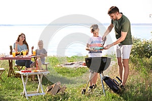 Young man with son near barbecue grill outdoors. Family picnic