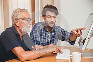 young man or son teaching his grandfather elderly dad learning to using computer at home.