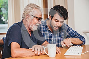 young man or son teaching his grandfather elderly dad learning to using computer at home.