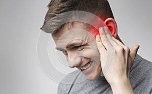 Young man with sore ear, suffering from otitis photo