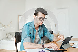 A young man sorts out household finances in the living room. Investments, buying an apartment and running your own