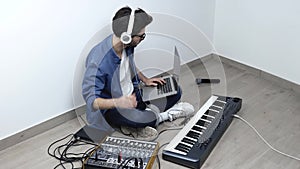 Young man in sound recording studio. Side view of guy hold laptop and use it together with sound mixing console