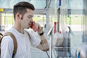 Young man speaking on public phone in station