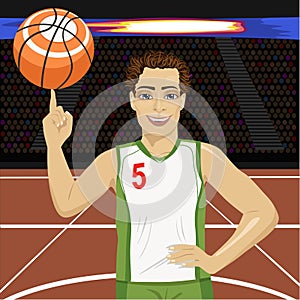 Young man spinning basketball ball with his finger on court in arena