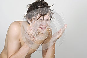 Young man splashing water on his face