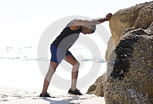 Young man sport training exercise stretching legs at the beach