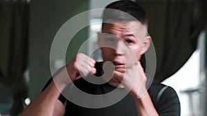 Young man in sportive t-shirt shadow boxing in front of a camera