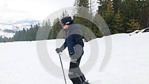 A young man in sports glasses is skiing in the mountains