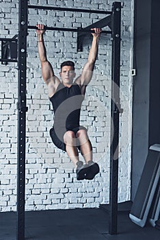 young man in sportswear doing pull ups on pull up bar