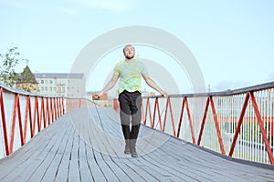 A young man in sportswear is jumping on jump ropes on bridge